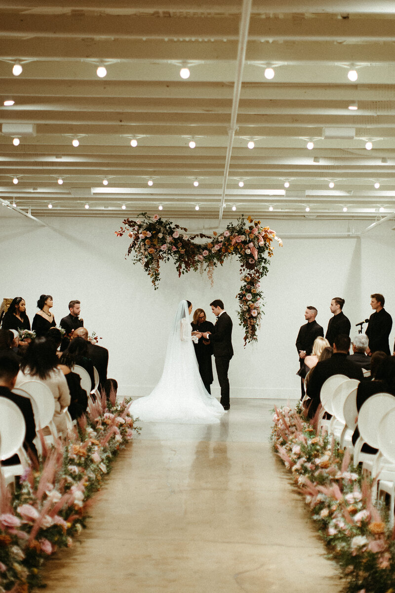 An eye-catching whimsical installation full of petal heavy roses and copper beech was the highlight of this art deco wedding. Terra cotta, burgundy, dusty pink, and other neutral florals warm up this ceremony. Designed by Rosemary and Finch in Nashville,  TN.