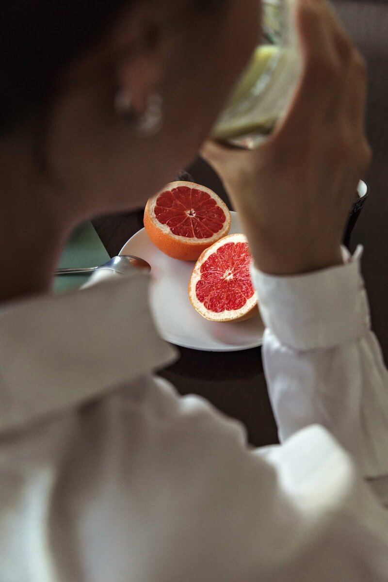 A woman eating grapefruit and eating a green smoothie for breakfast. ITN teaches you how to prioritize physical nutrition.