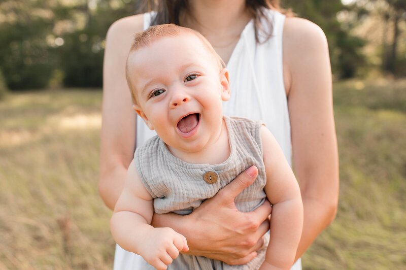 baby leaning towards camera in moms arms by Cypress Family Photographer