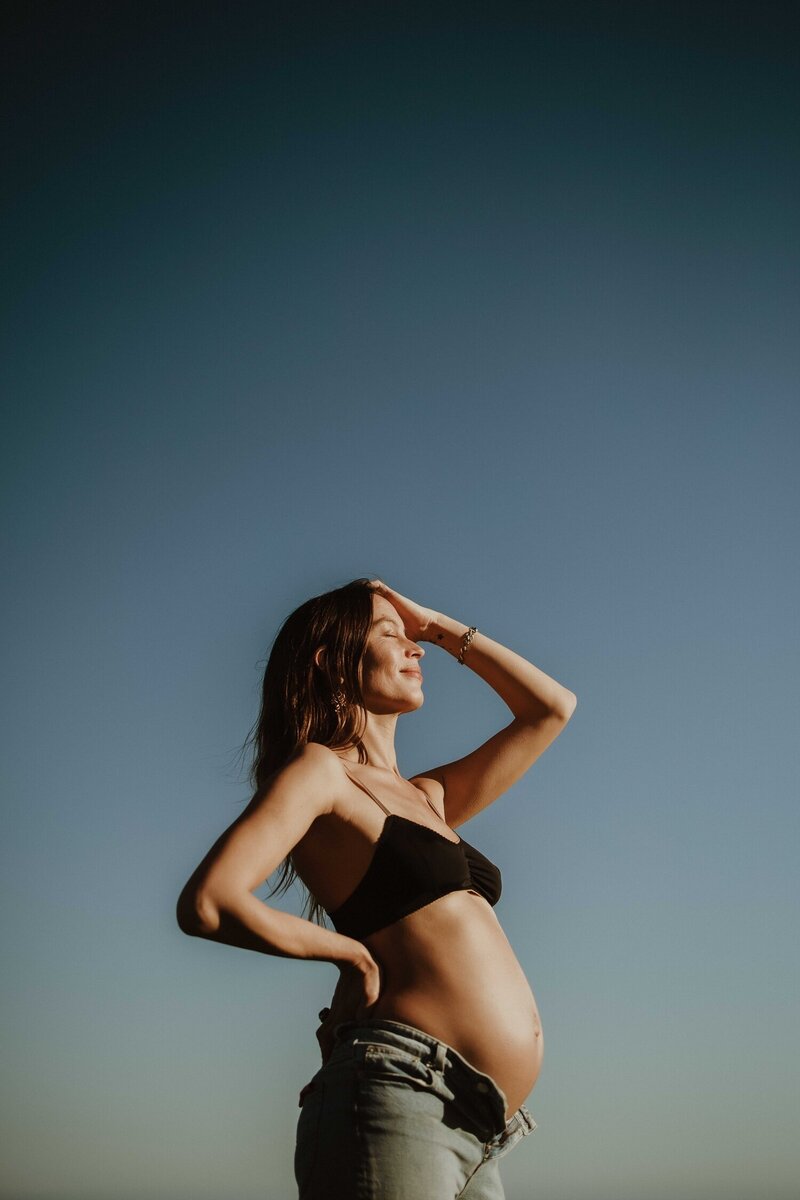 Pregnant woman looking into the distance against blue sky, Sydney maternity photography session.