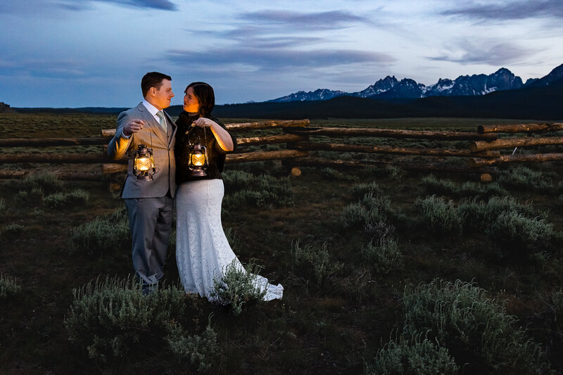 Couple facing each other holding lanterns during blue hour Glacier National Park.
