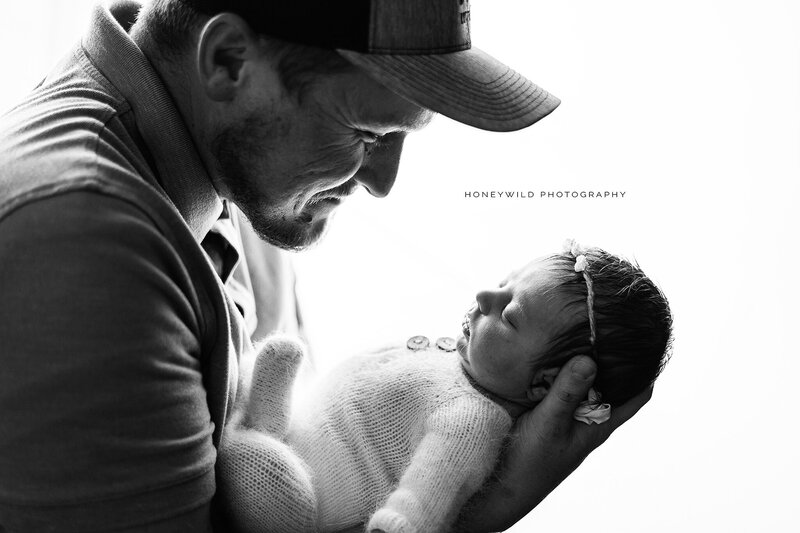 Black-and-white portrait of a father holding his newborn baby close, captured in an emotional and timeless style by Honeywild Photography in Grand Rapids, MI