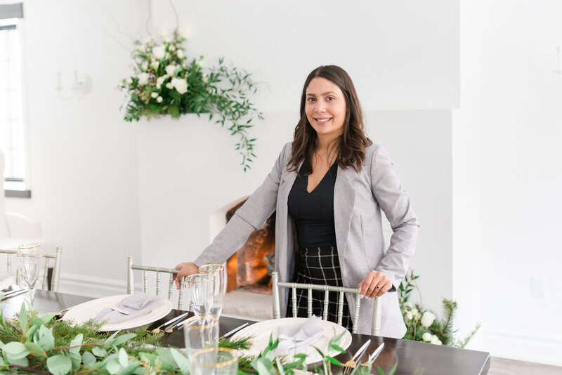 Wedding Planner standing over a wedding table scape with lush greenery