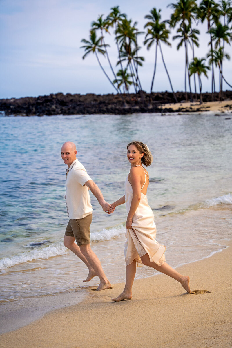 Couple running across the beach for engagement photos by taken by Big Island photographer, Hawaii Adventure Portraits