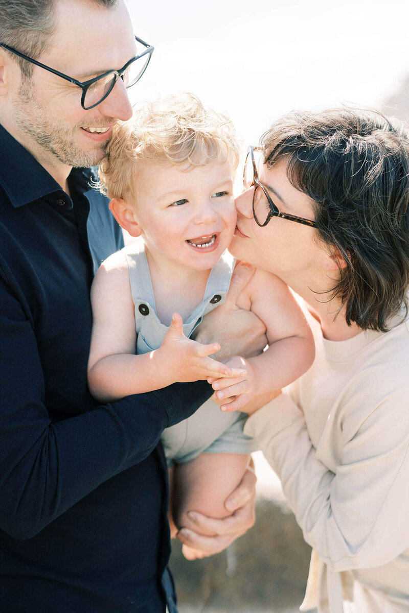 close up candid of parents playing with their toddler at the beach