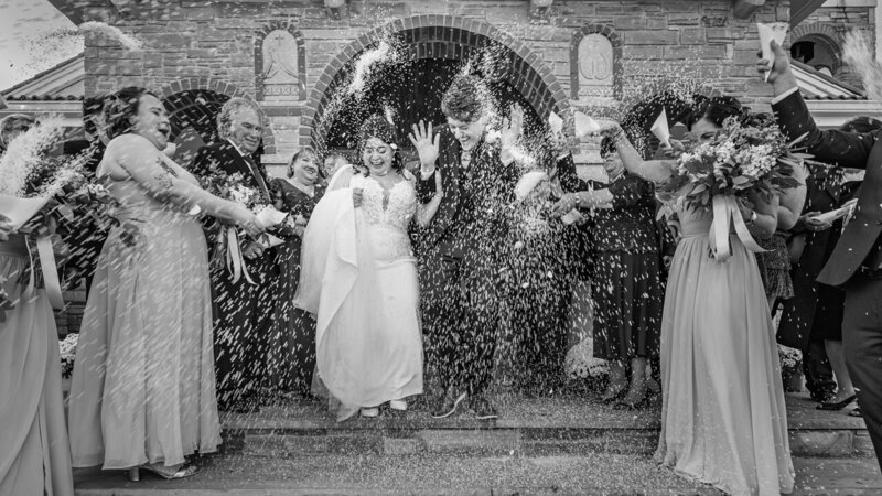 Bride and groom being showered with rice as they exit a Greek church, capturing a joyful and celebratory wedding tradition.
