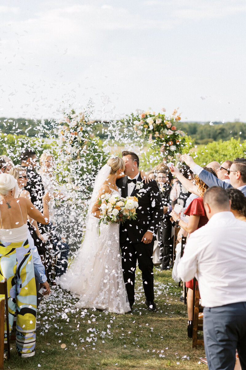Bride & Groom's first kiss during ceremony as confetti is thrown at Ravine Vineyard Estate Wedding in Niagara-on-the-Lake