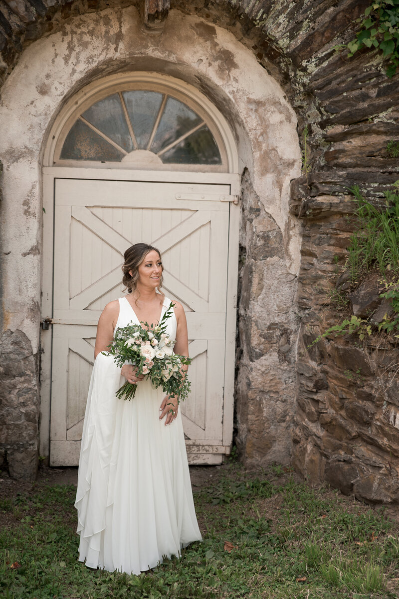 Bride standing in front of a door surrounded by stone