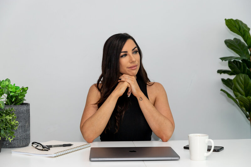 Woman sits at a desk with closed laptop