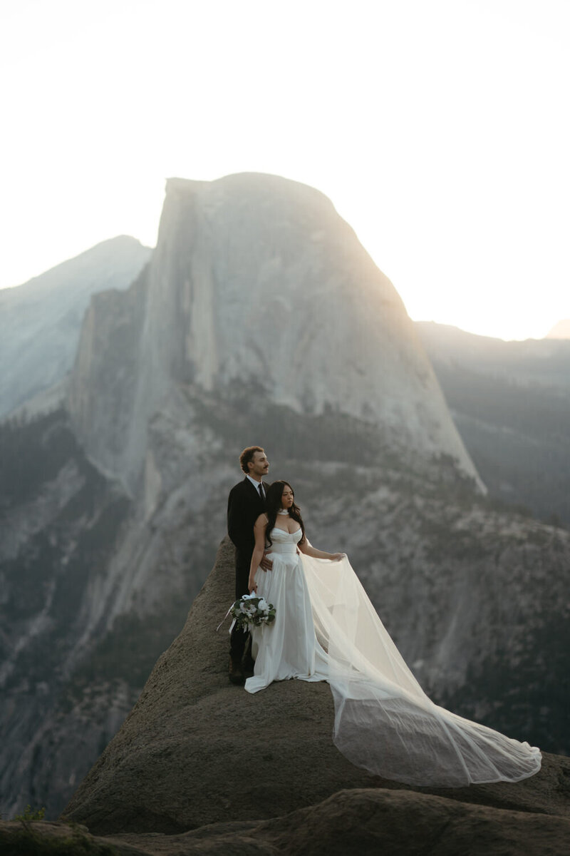 Bride and groom look off into the distance with half Dome in the background of their Yosemite elopement