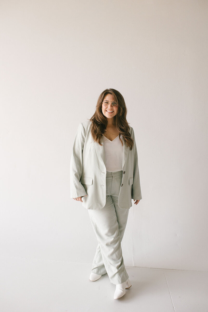 A woman wearing a mint green suit paired with white sneakers, exuding a stylish and modern look.