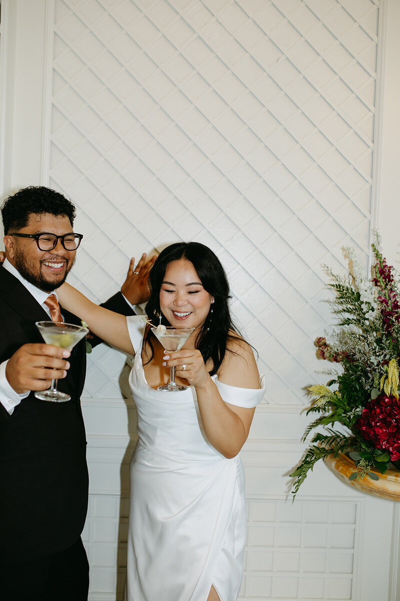 A bride and groom pose with martini cocktails during their wedding reception in Bay Area