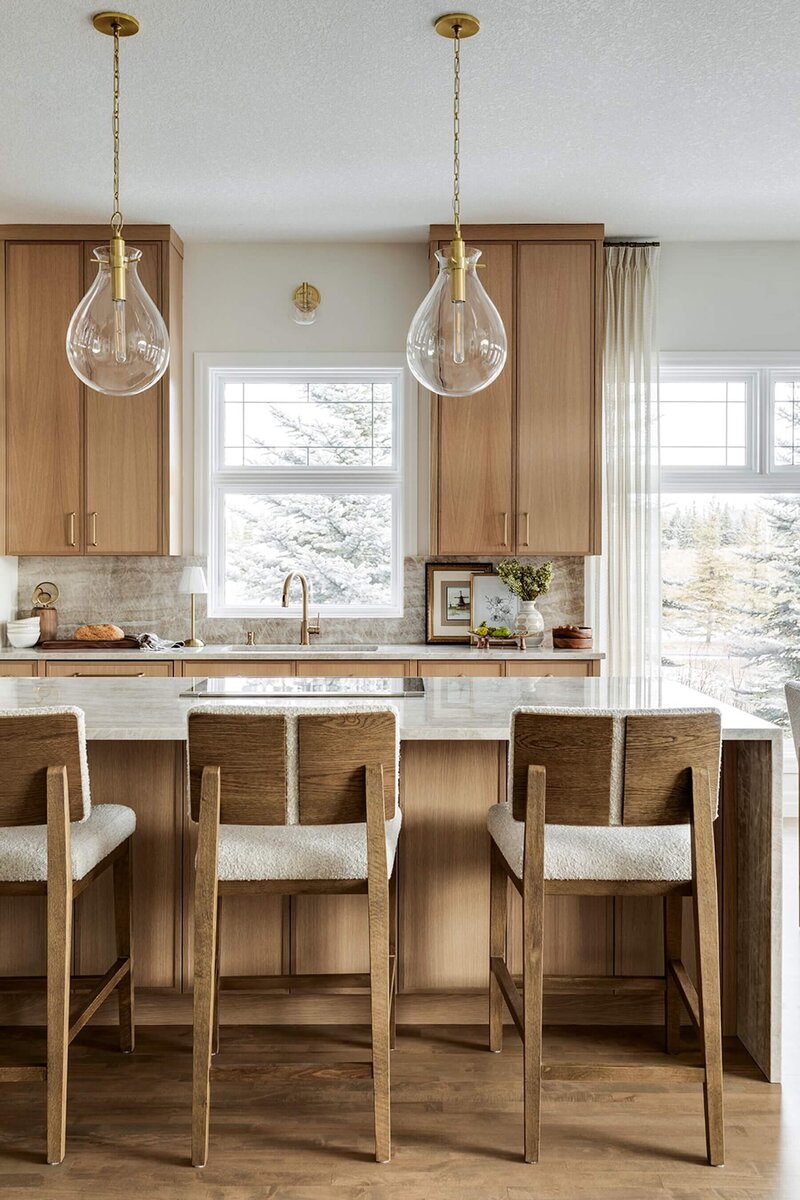 Kitchen renovation with quartzite, wooden counter stools and glass pendants. 