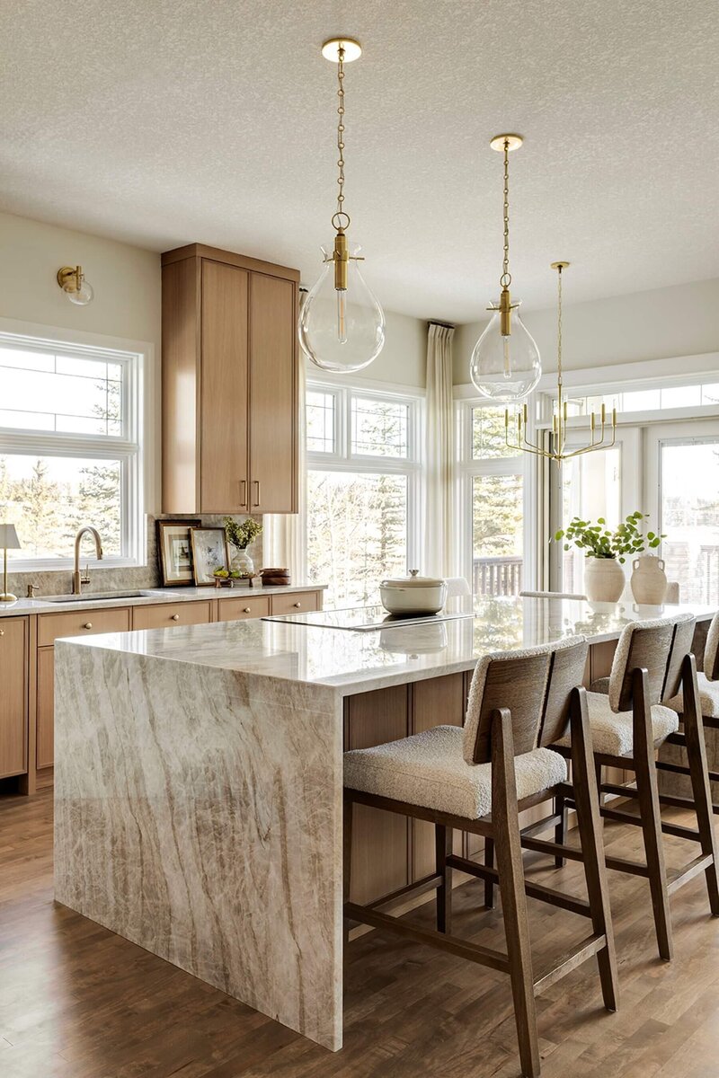 Kitchen renovation with quartzite, wooden counter stools and glass pendants. 