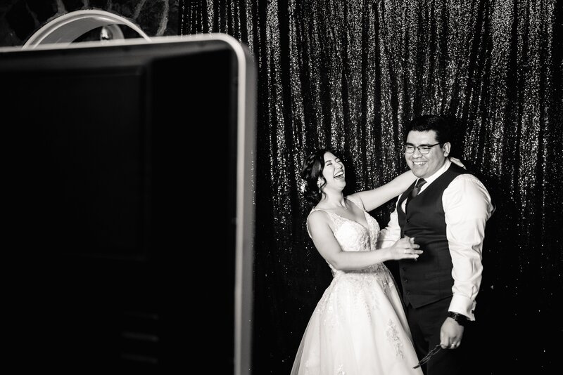 a wedding couple takes photos at a photo booth. 