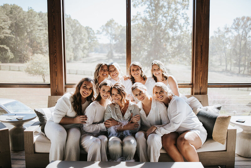 Bride and bridesmaid share a joyful moment getting ready for an Atlanta wedding, hugging in soft natural light.