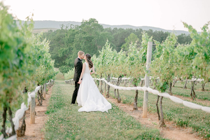 Bride and groom at Veritas Winery, a Charlottesville wedding venue, kissing in the vineyard.