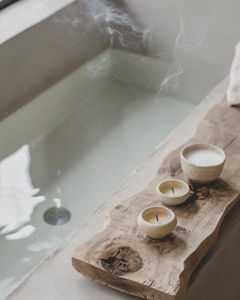 Modern rectangle tub with slab of naturally cured wood with candles and bath salts on top