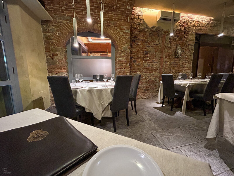 Interior dining room with exposed brick and white tablecloths at Osteria dell'Enoteca in Florence, Italy