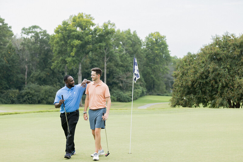 Two men share a celebratory moment on the green of a Columbia, SC, golf course, exuding camaraderie and success. This commercial branding photograph captures the essence of networking and leisure in a professional setting, ideal for showcasing corporate retreats, business relationships, and lifestyle branding photography in South Carolina.