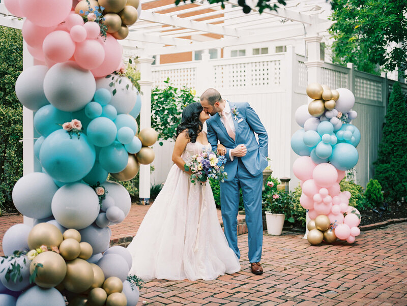 bride and groom kissing around colorful balloons
