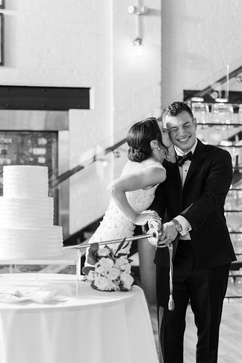 Fun and authentic moment from reception while groom cuts cake with a sword