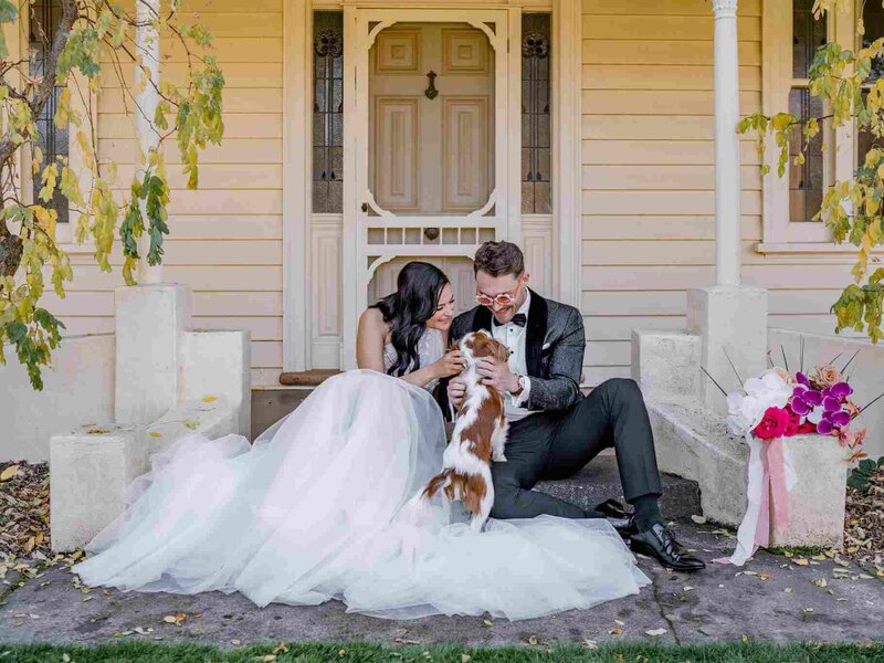 couple patting a dog while sitting on the front porch