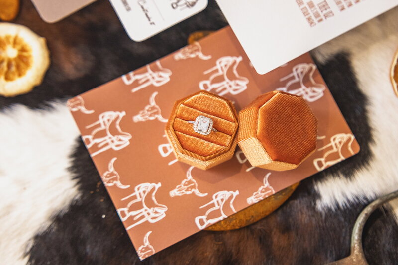 Salt Lake City wedding detail photography featuring an engagement ring in a velvet box on a Western-inspired invitation. Moonlit Photo Utah bridal detail shots with luxury flat-lay styling for weddings and elopements.