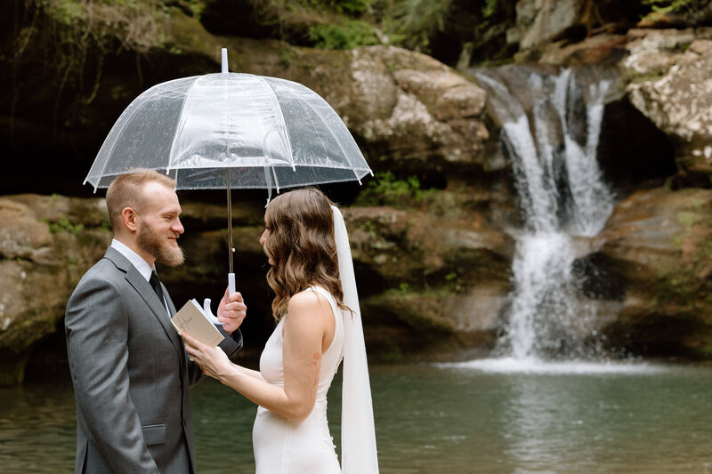 Bride and groom sitting on a bench in the Akron Art Museum with a gallery of paintings behind them. 