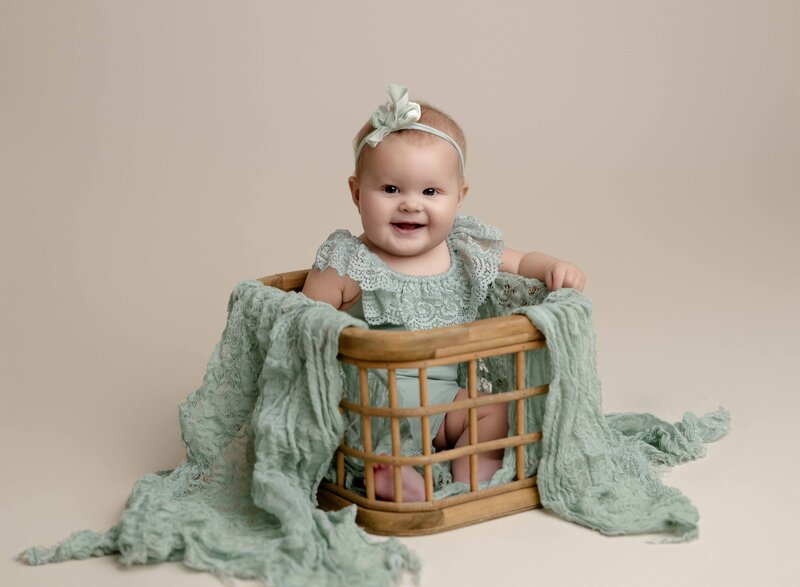 Baby girl in mint romper, sitting up in a wooden crate, for her Milestone photoshoot in Atlanta. Photo by Jenni Nikki Photography.