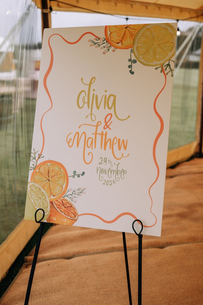 italian citrus yellow and orange themed wedding signage in stretch tent at farm chapel waimumu