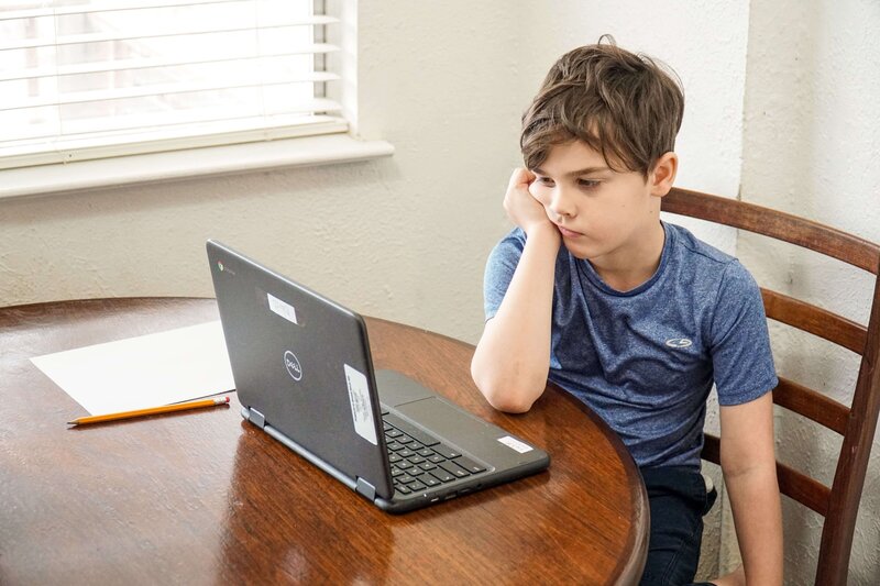 A sad student sitting at their desk, staring at their laptop