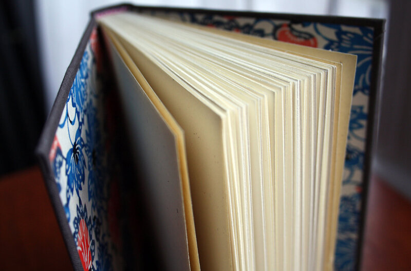 View of the inside of a grey hardcover book with cream colored pages and floral endpapers