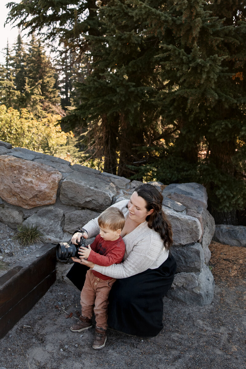 photographer helping a child take a photo in a forested park