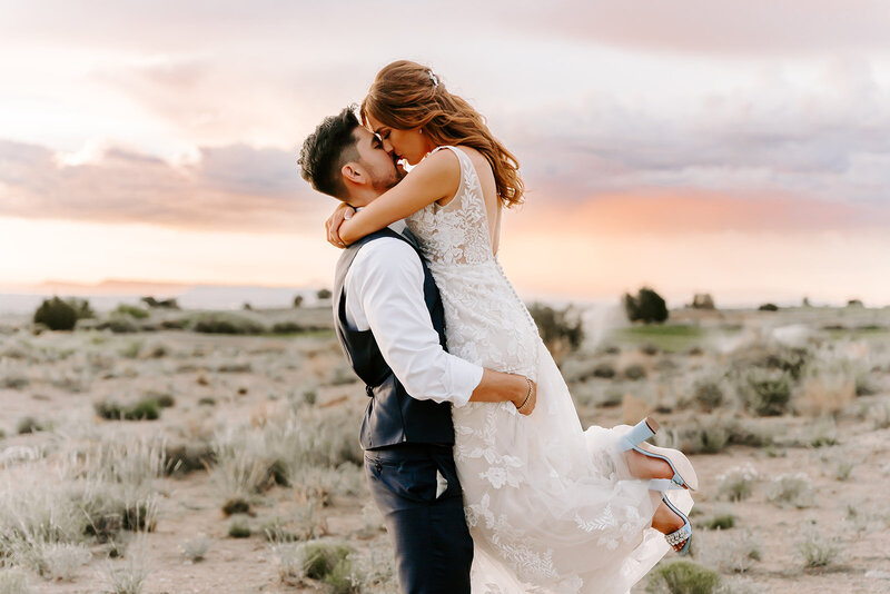 bride and groom in the desert kissing on their wedding day