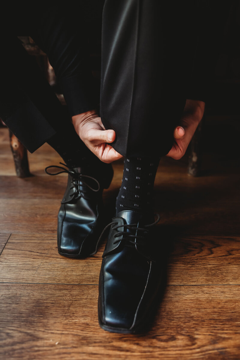 Groom tying his dress shoes before tying the knot with his new bride