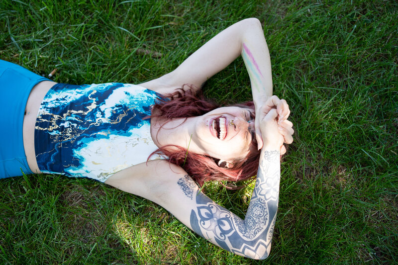 Sarah lays on the grass laughing with hands on her forehead