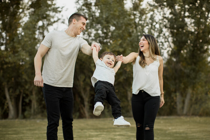 mom and dad swing their child between them while walking and laughing