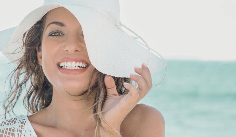 Smiling woman with white floppy beach hat