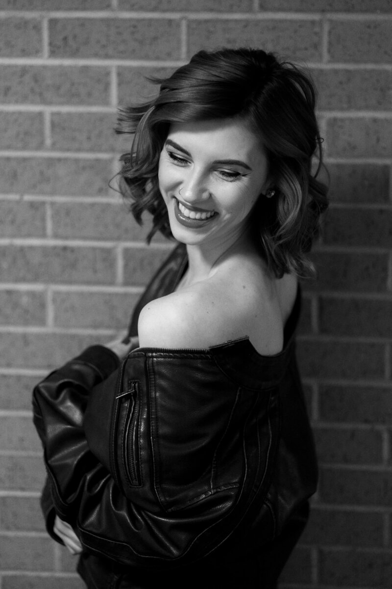 Colorado Springs Boudoir Photographer in  leather jacket against brick wall