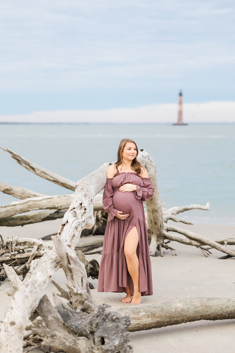 expecting mom holding her belly by the lighthouse in Folly Beach