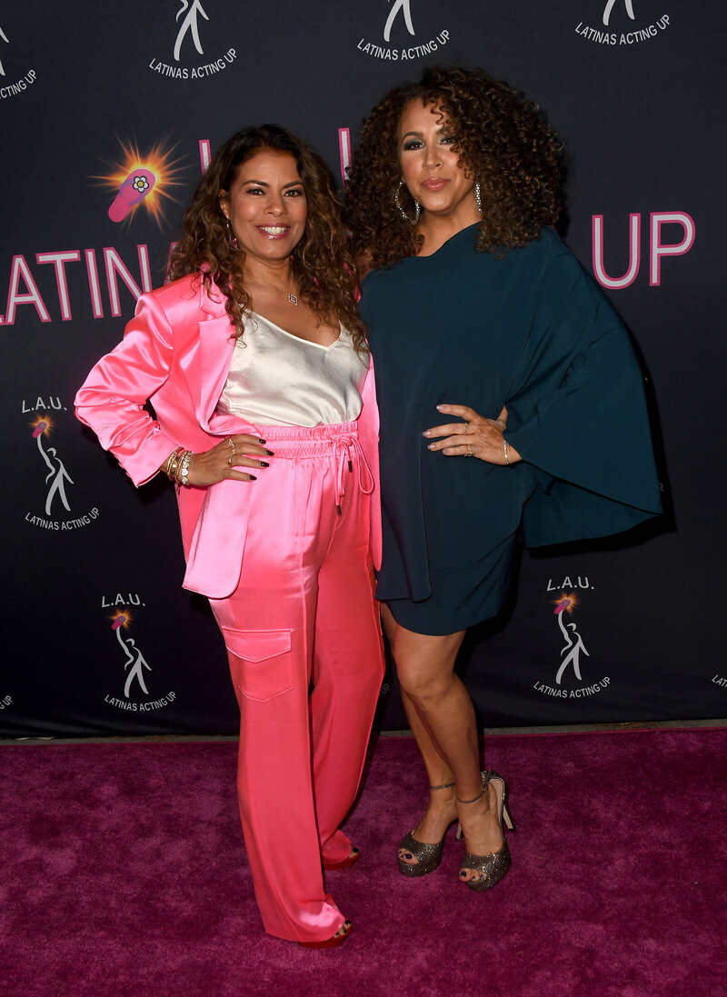 Diana Maria Riva and Lisa Vidal, co-founders of Latinas Acting Up, standing together on a purple carpet at an LAU event.