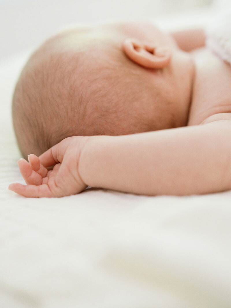 A close-up of a baby's arm and backside of the head at a newborn photography session in Richmond by Katie Stansfield Photography.