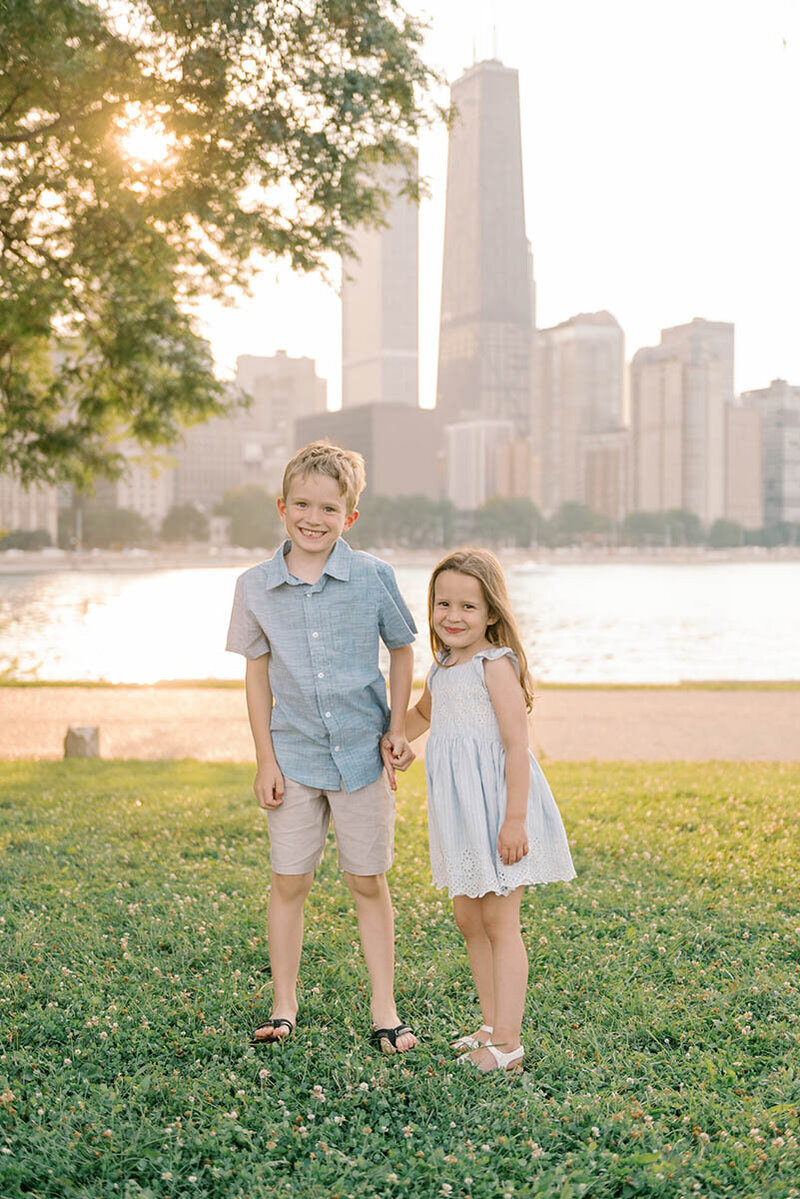 Young boy and girl holding hands in front of the Chicago skyline at Milton Olive Lee Park by Chicago family photographer Kristen Hazelton