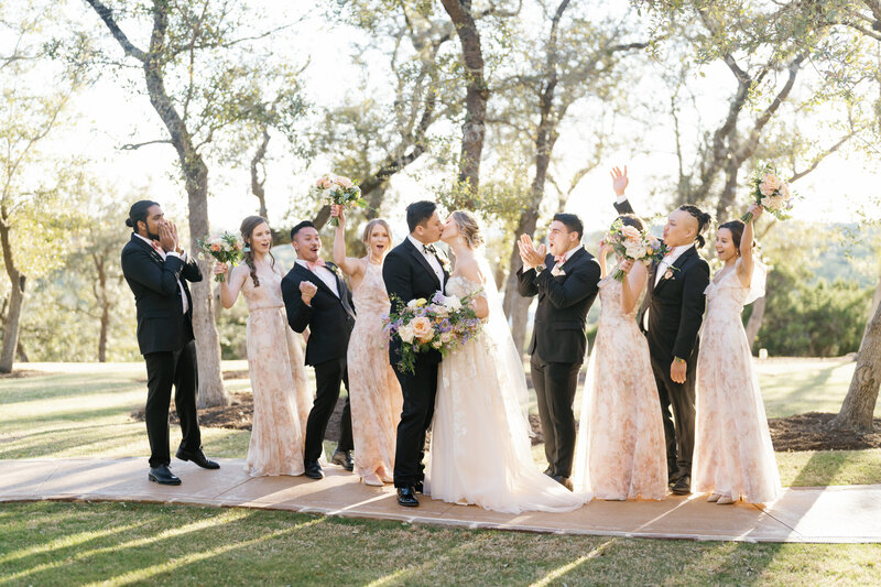 Bride and groom kissing with their reception and guests in the background