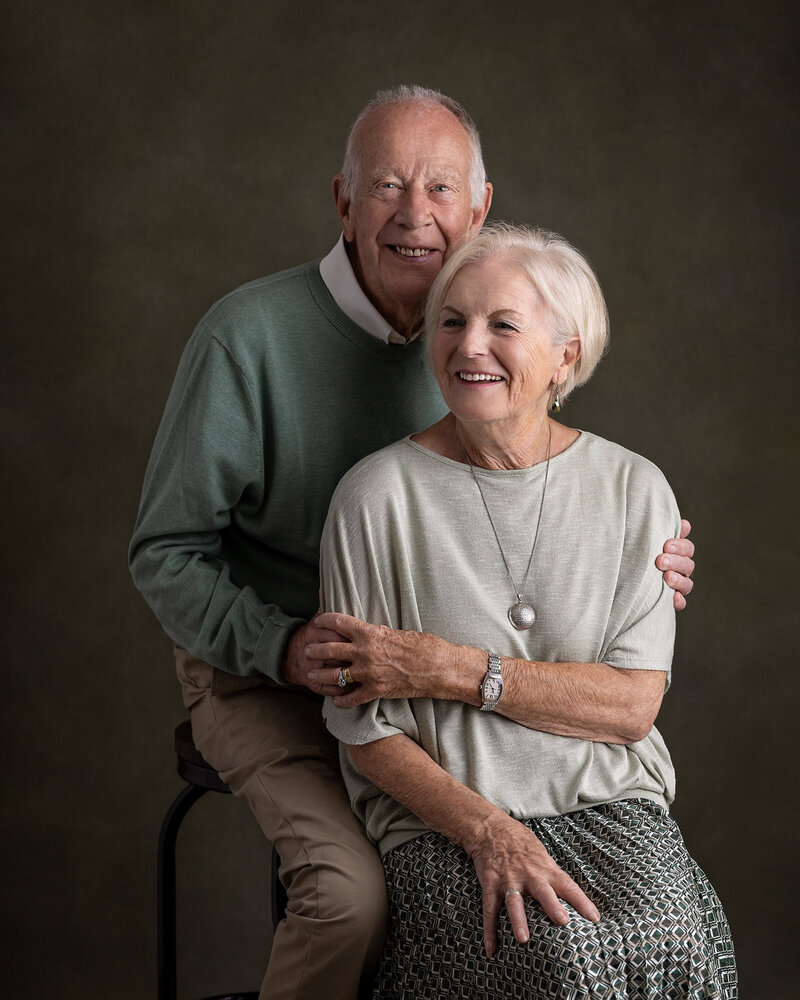 Studio portrait of smiling elderly couple on painted green background