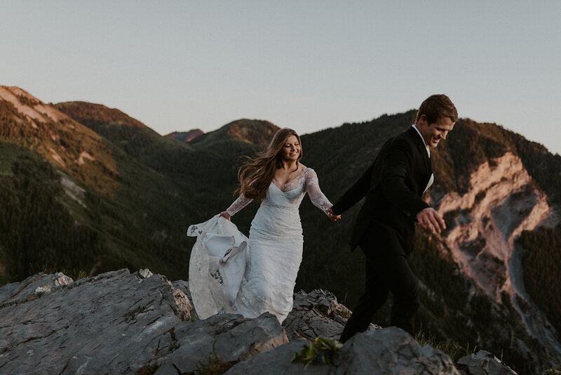 bride and groom holding hands walking on top of a mountain