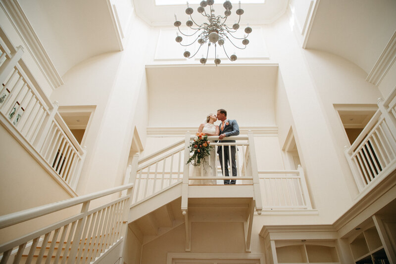 A bride and groom kiss on a staircase, the moment is elegant and sophisticated and very symmetrical