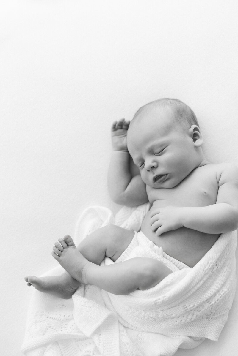 Zoomed in newborn portrait of a baby in a blanket with hands o the chin while sleeping by Suzanne Karp Photography