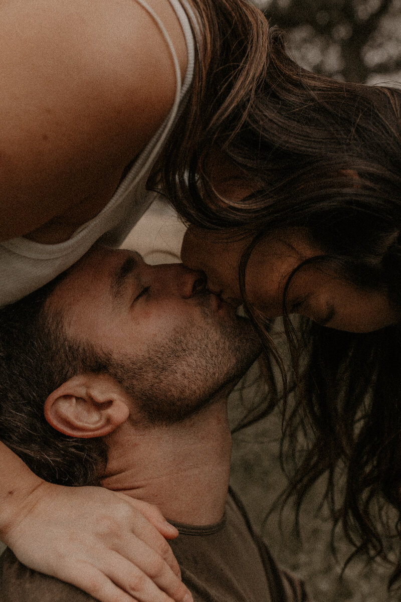A woman leaning over to kiss her man upside down. 